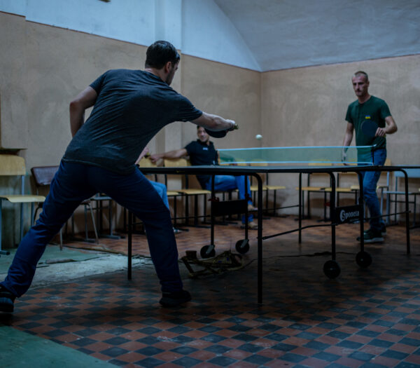 Zwei Personen spielen Tischtennis in einem abgedunkelten Raum